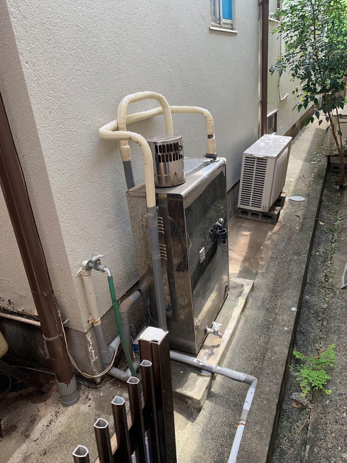 八代市千丁町太牟田の交換前・長府製作所製の石油給湯器・使用年数約14年・灯油代高騰や、灯油を補充する作業の負担